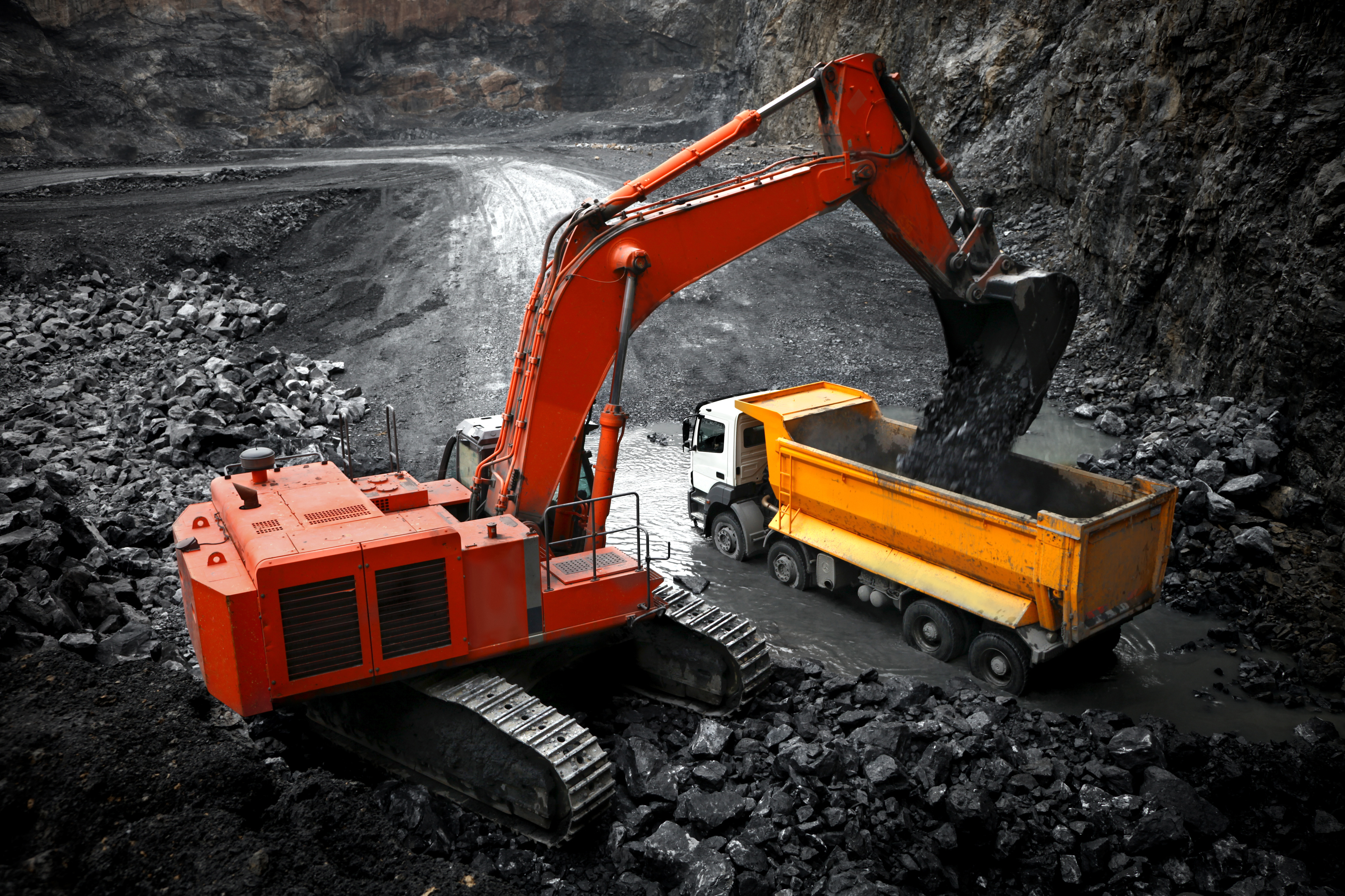 Mining excavator and haul trucks operating on site
